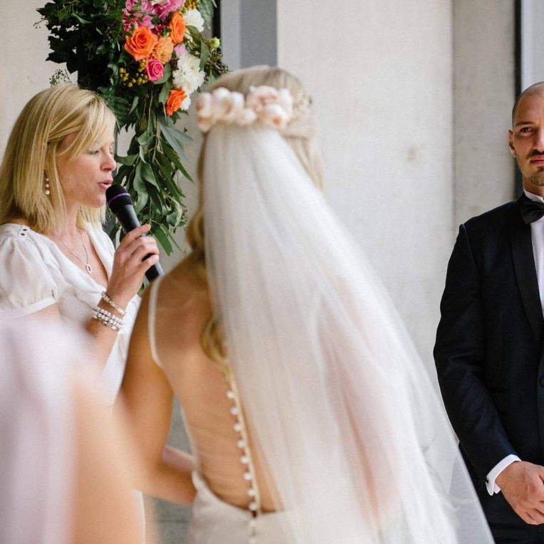 Nicole leading the vows beneath a floral arch