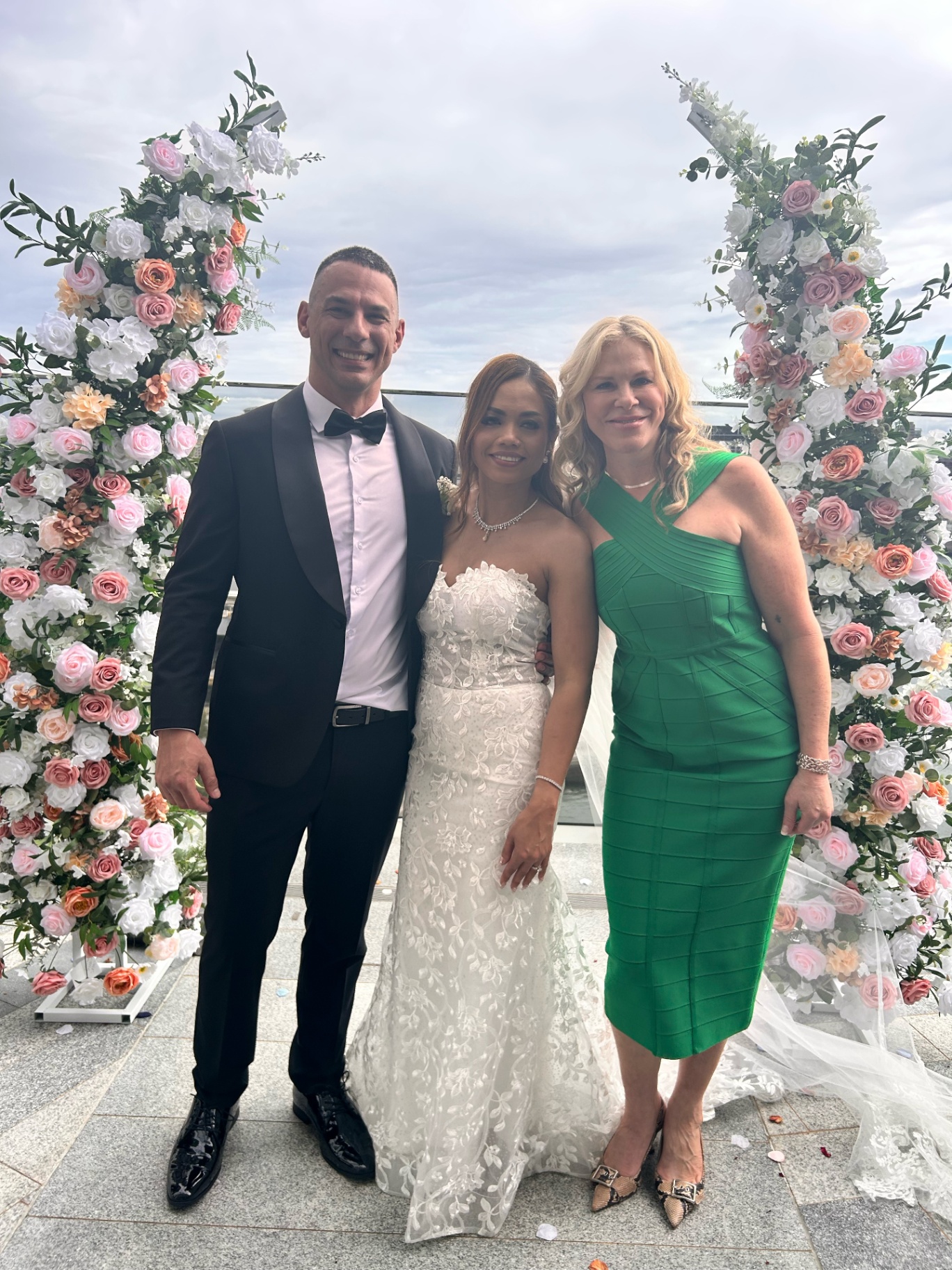 Nicole with newlyweds framed by a flower-filled harbour arch